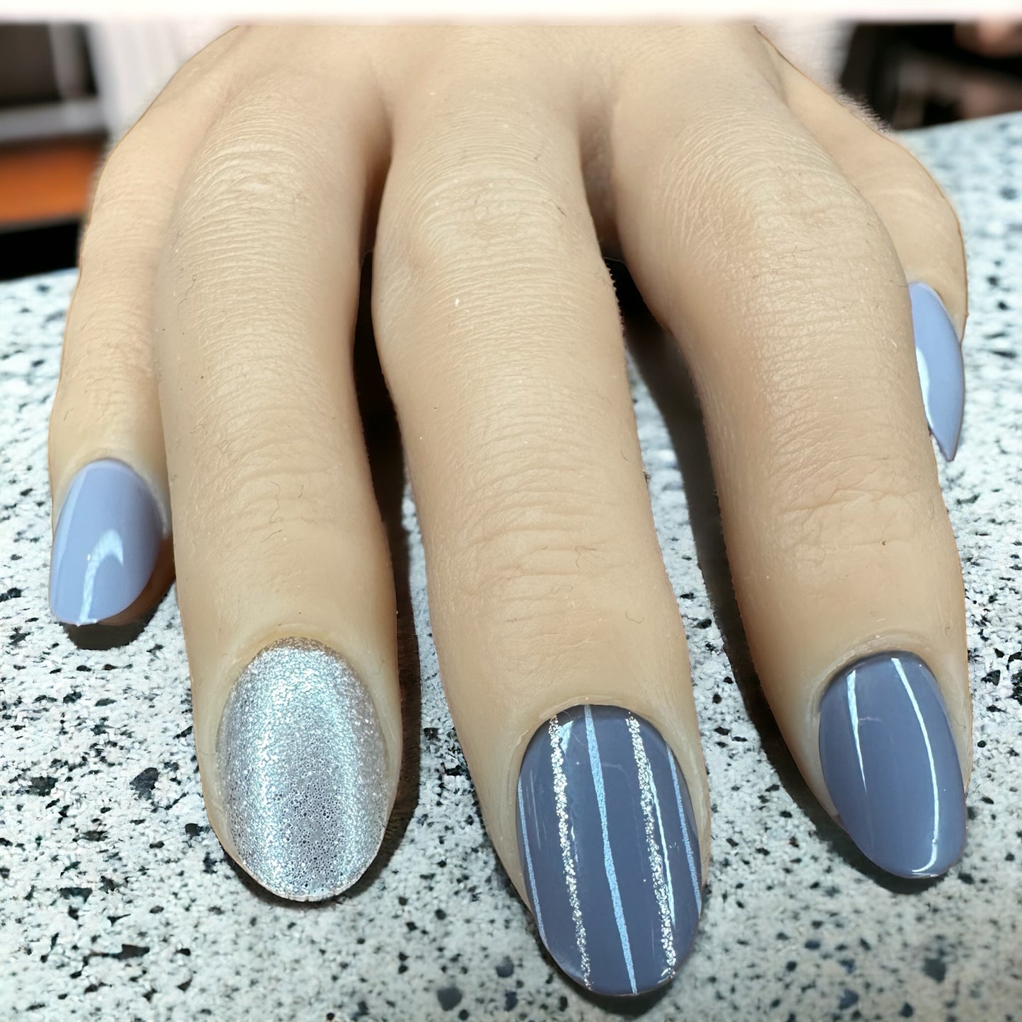 Hand with fingers adorned in sparkly grey monochrome short round press-on nails
