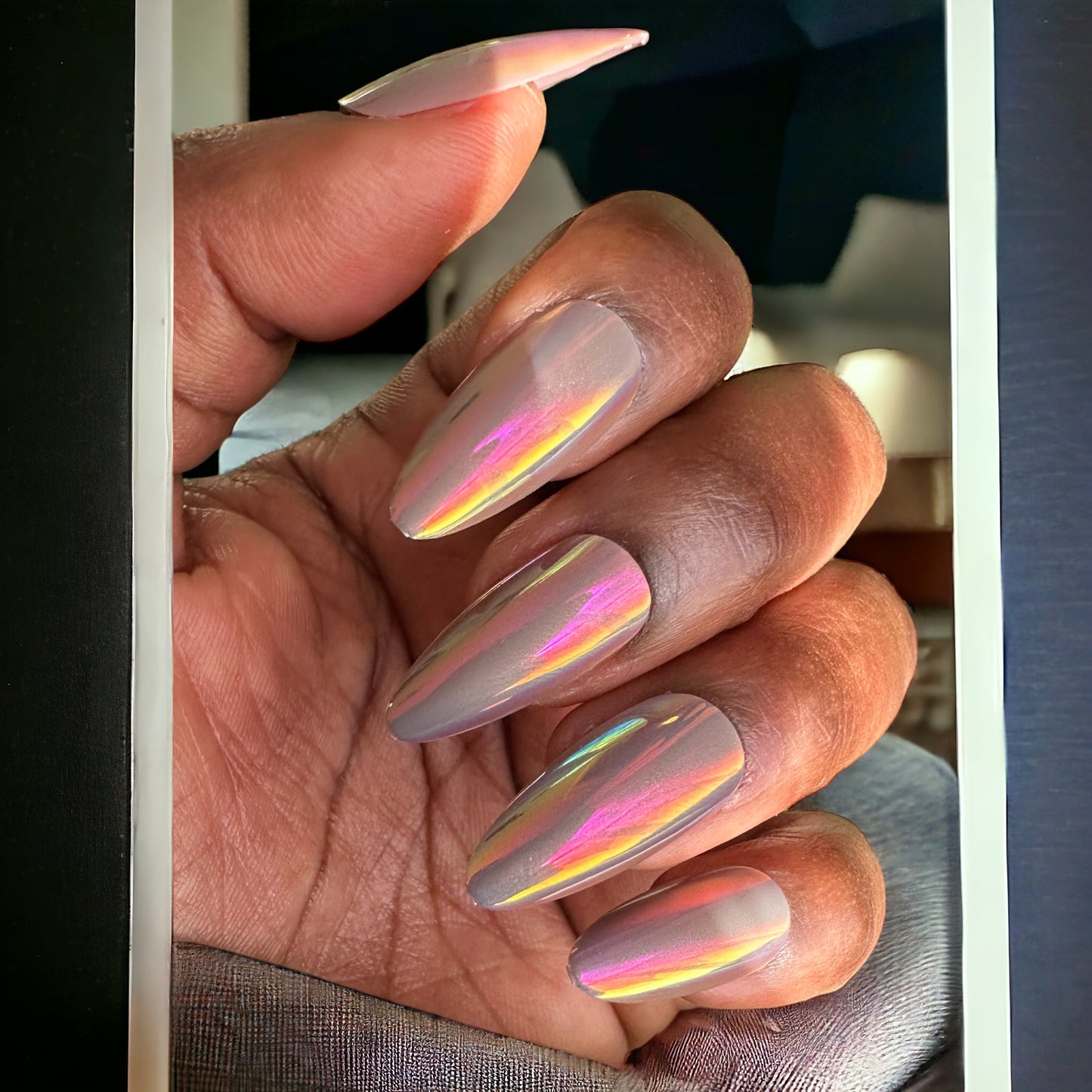 Fingers with medium almond-shaped press-on nails in grey chrome with pink hues color