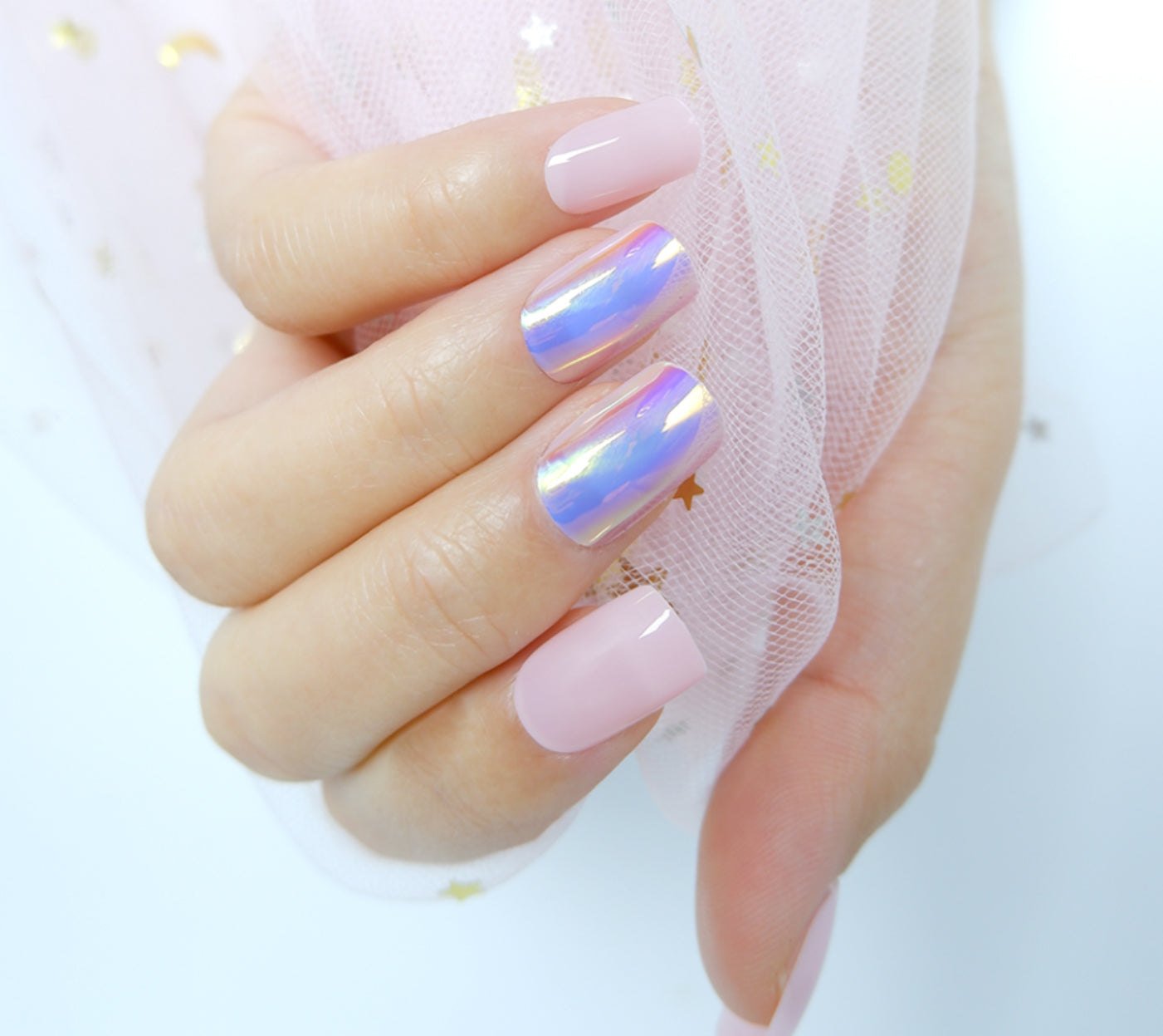 Close-up of short of a hand with square-shaped pink chrome press-on nails gripping a white mesh fabric against a plain white backdrop